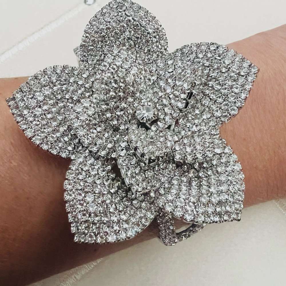 A silver colored bracelet with a giant flower.